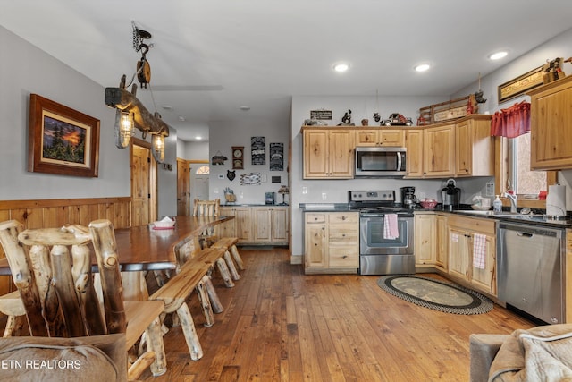 kitchen with hardwood / wood-style flooring, a sink, dark countertops, recessed lighting, and stainless steel appliances