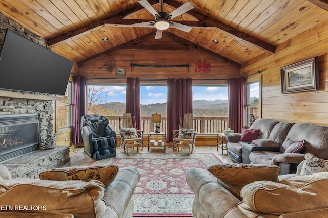 living area with a ceiling fan, a mountain view, wooden ceiling, wood walls, and vaulted ceiling with beams