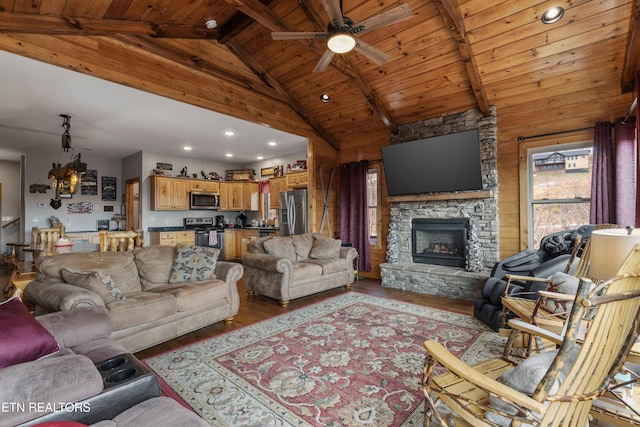 living room featuring a stone fireplace, beamed ceiling, ceiling fan with notable chandelier, and wood finished floors