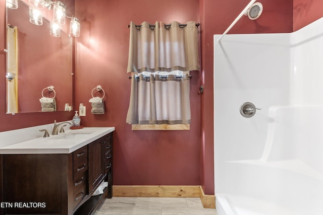 bathroom featuring baseboards, vanity, and walk in shower