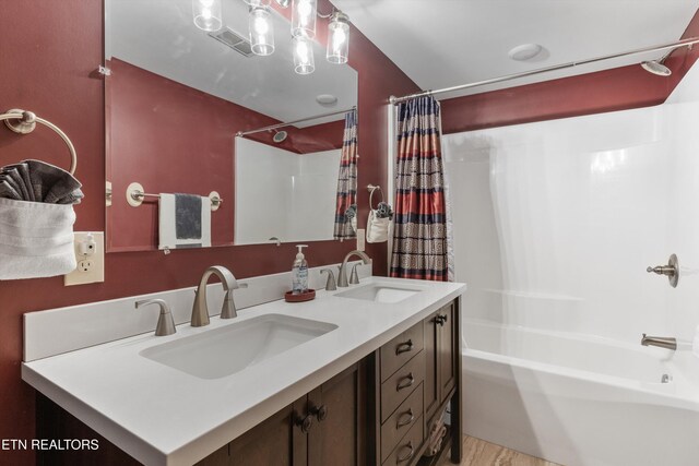 full bathroom featuring double vanity, visible vents, shower / tub combo with curtain, and a sink