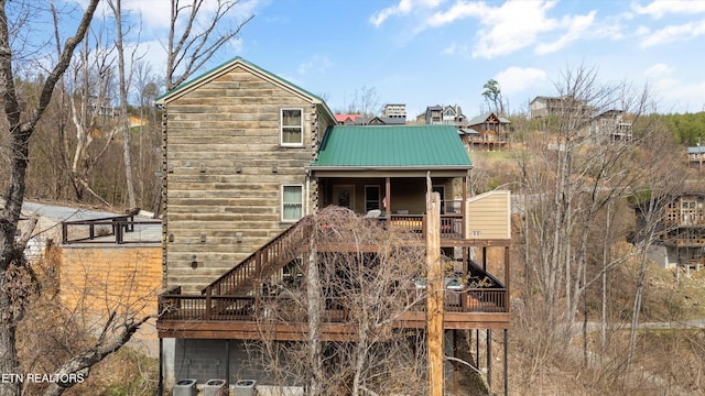 back of property with a wooden deck, stairway, and metal roof