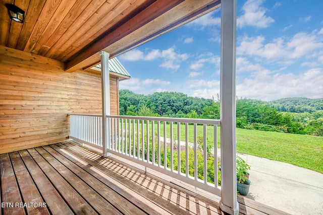 deck with a yard and a view of trees