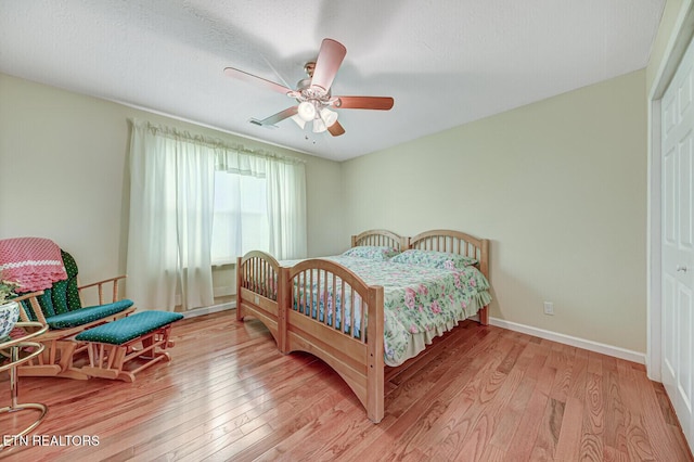 bedroom featuring baseboards, a ceiling fan, and light wood finished floors