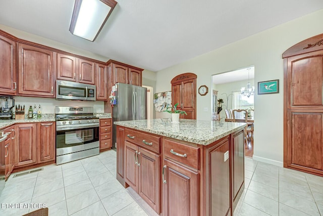 kitchen with light tile patterned floors, light stone countertops, visible vents, stainless steel appliances, and a center island