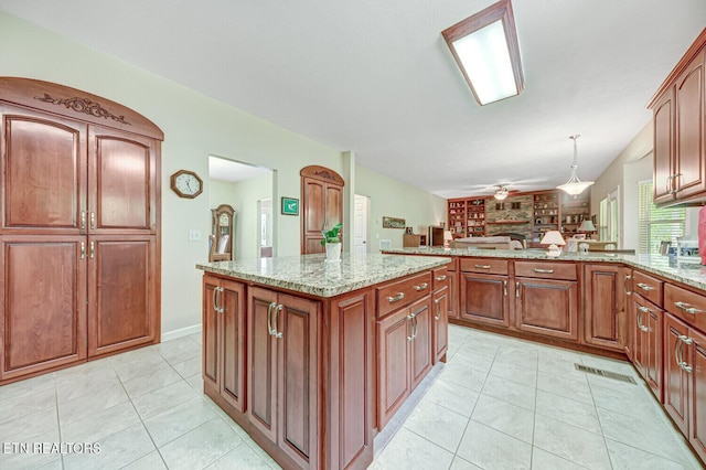 kitchen featuring light tile patterned floors, decorative light fixtures, a peninsula, and light stone countertops