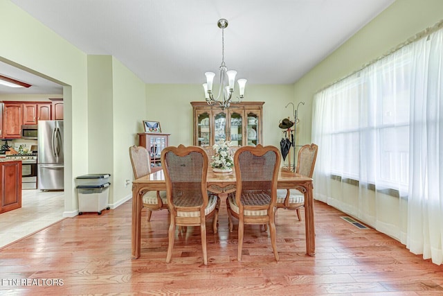 dining room featuring visible vents, baseboards, light wood-type flooring, and an inviting chandelier