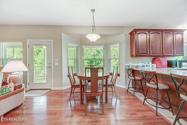 dining space with light wood-type flooring and baseboards