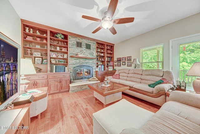 living area with built in shelves, light wood-type flooring, and ceiling fan