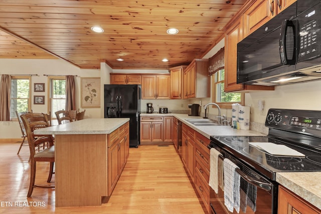 kitchen featuring black appliances, a sink, a kitchen breakfast bar, wooden ceiling, and light wood finished floors