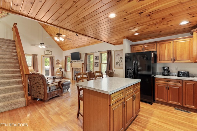 kitchen with light countertops, a kitchen breakfast bar, black fridge with ice dispenser, and open floor plan