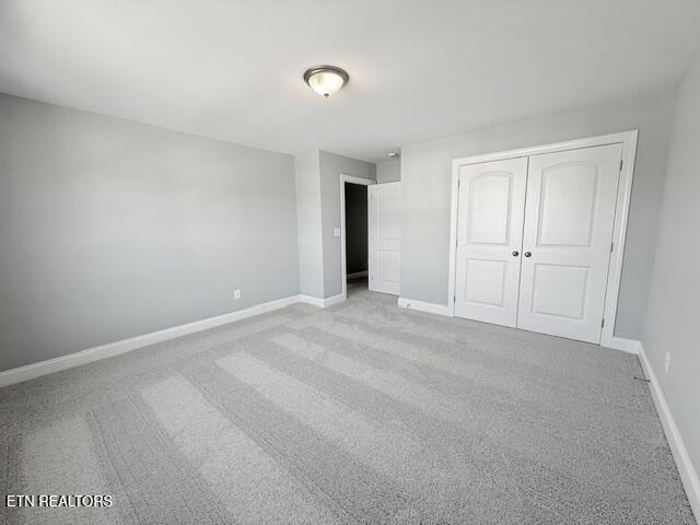 unfurnished bedroom featuring a closet, carpet, and baseboards