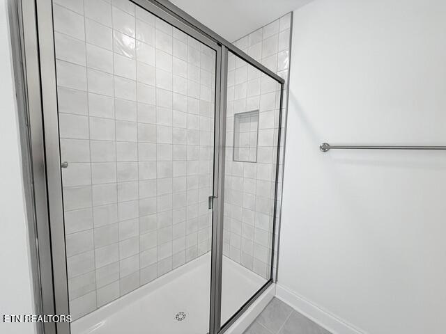 full bath featuring a shower stall, baseboards, and tile patterned floors