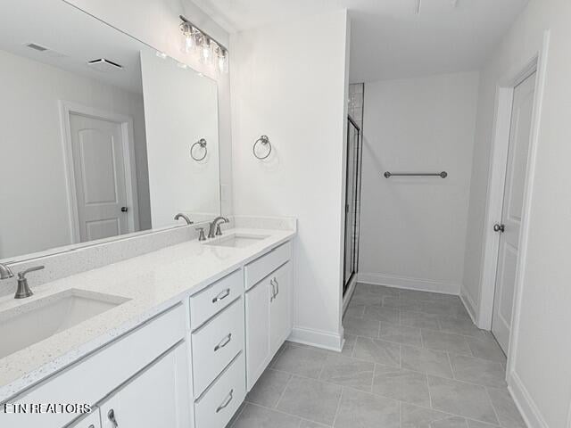 bathroom with double vanity, a stall shower, baseboards, and a sink