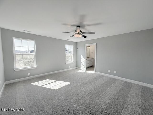 unfurnished bedroom featuring visible vents, baseboards, carpet floors, ensuite bath, and a ceiling fan