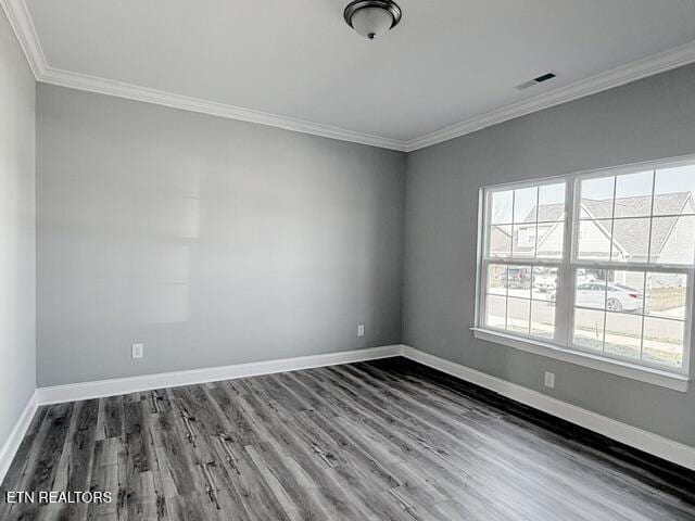 empty room featuring wood finished floors, baseboards, and ornamental molding