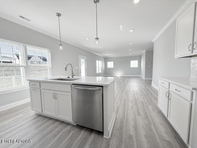 kitchen featuring visible vents, crown molding, baseboards, stainless steel dishwasher, and a sink