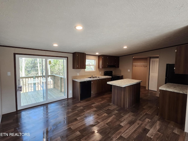 kitchen featuring dark wood-style floors, black appliances, light countertops, dark brown cabinets, and a center island