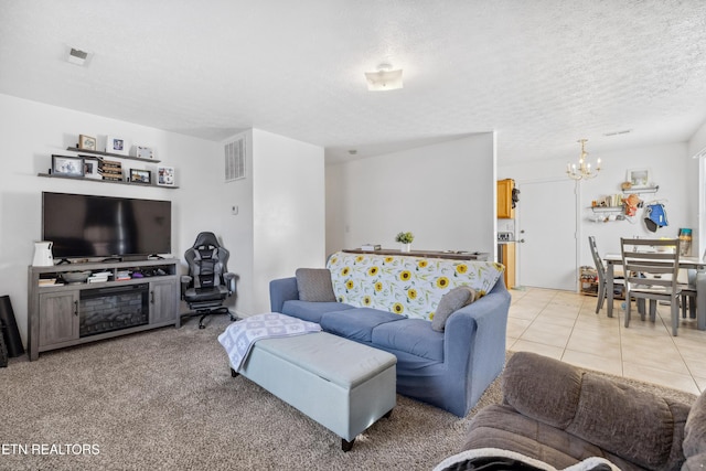 living room with a notable chandelier, light tile patterned flooring, visible vents, and a textured ceiling