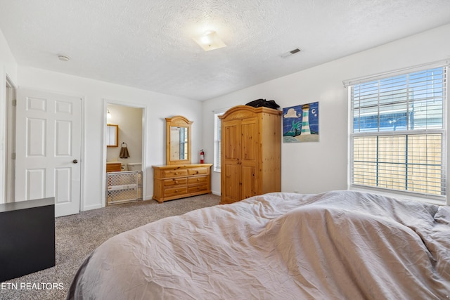 bedroom with carpet flooring, visible vents, connected bathroom, and a textured ceiling