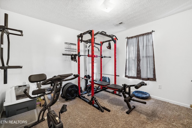 exercise room with carpet flooring, baseboards, visible vents, and a textured ceiling