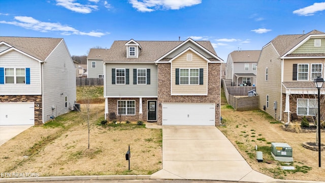 view of front of house with fence, an attached garage, a shingled roof, concrete driveway, and brick siding