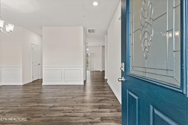 entryway featuring visible vents, an inviting chandelier, dark wood-style flooring, and a decorative wall