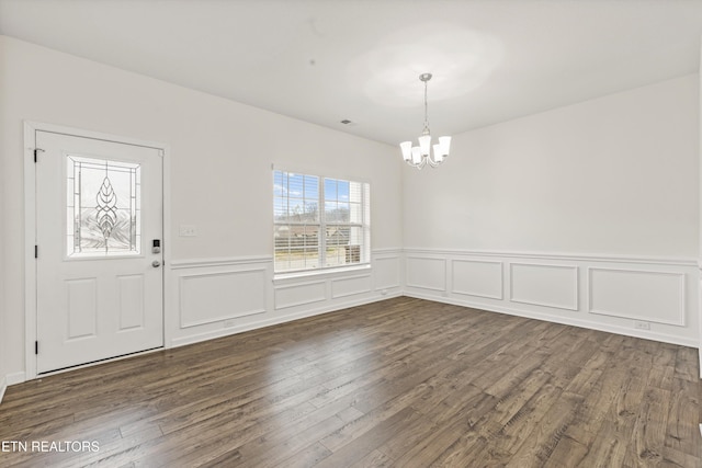 unfurnished dining area with a chandelier, visible vents, and dark wood-type flooring