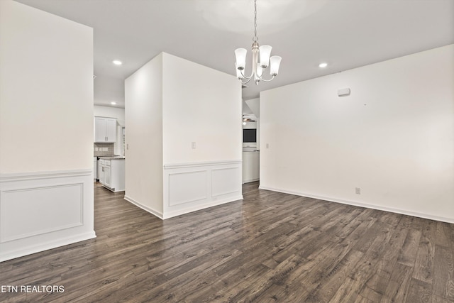 interior space featuring a chandelier, a decorative wall, wainscoting, and dark wood-type flooring