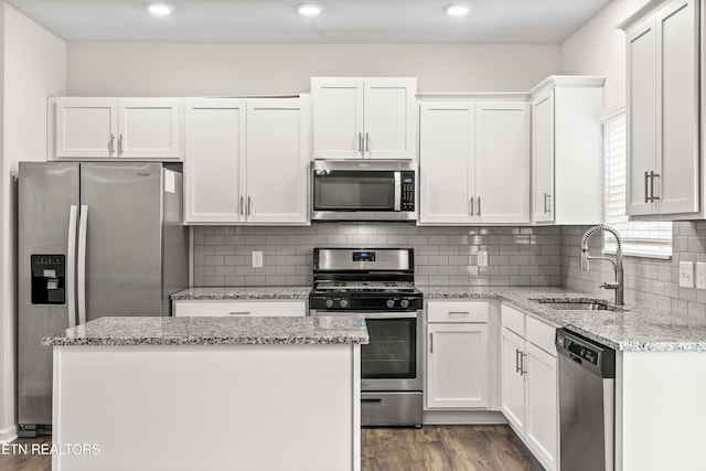 kitchen with a sink, a kitchen island, appliances with stainless steel finishes, white cabinetry, and dark wood-style flooring