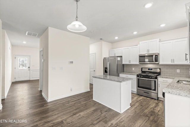 kitchen with tasteful backsplash, visible vents, a kitchen island, stainless steel appliances, and dark wood-style flooring