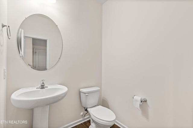 bathroom with toilet, wood finished floors, and baseboards