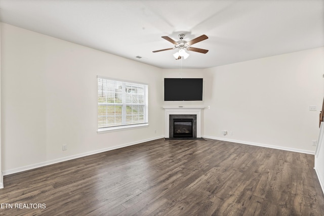 unfurnished living room featuring dark wood-style floors, a fireplace with flush hearth, a ceiling fan, and baseboards