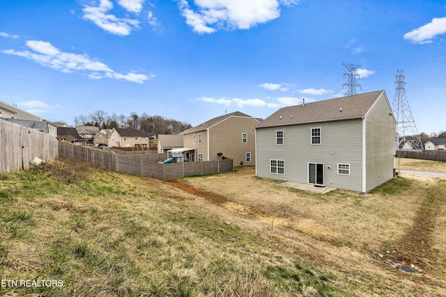 rear view of property featuring a yard, a patio, and a fenced backyard