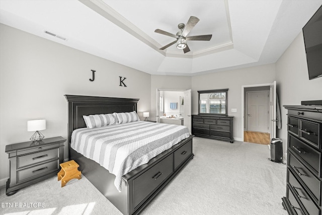 bedroom with visible vents, baseboards, a tray ceiling, light carpet, and a ceiling fan