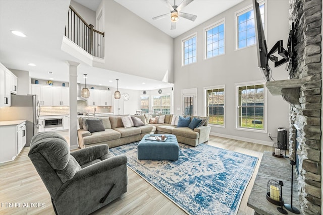 living area with ceiling fan, baseboards, light wood-style flooring, and a fireplace