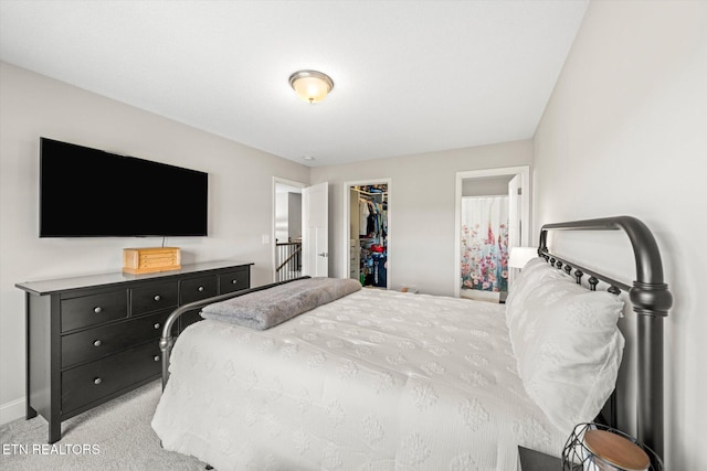 bedroom featuring a closet, baseboards, light colored carpet, and a spacious closet