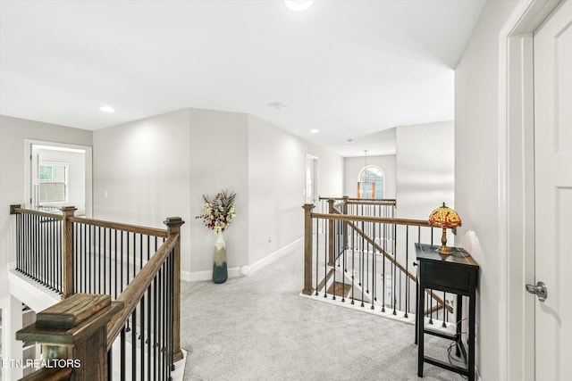 hallway featuring carpet, an upstairs landing, and a healthy amount of sunlight