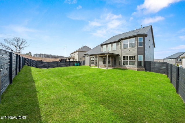 rear view of property featuring a patio, a yard, and a fenced backyard