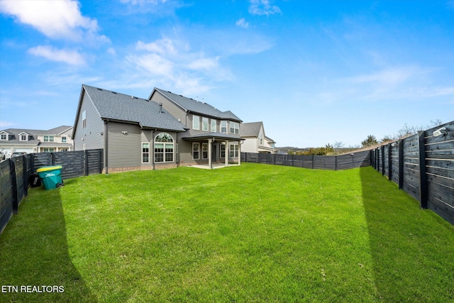 rear view of house featuring a lawn, a patio, and a fenced backyard