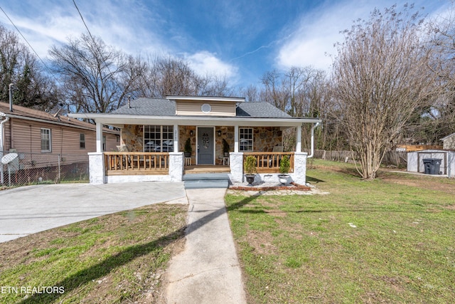 bungalow featuring driveway, a front lawn, stone siding, a porch, and fence