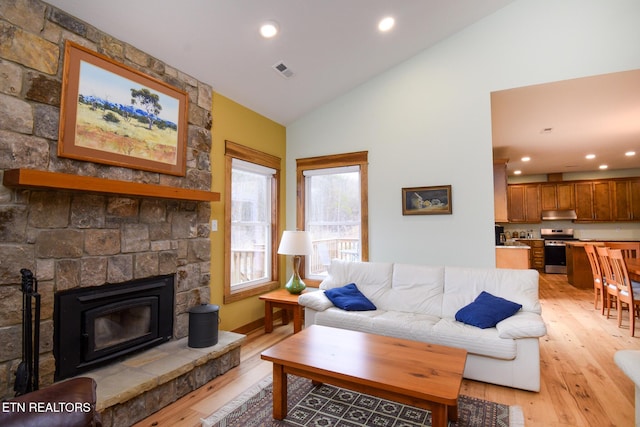 living room with a stone fireplace, recessed lighting, visible vents, and light wood finished floors