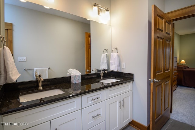 bathroom featuring a sink, connected bathroom, baseboards, and double vanity