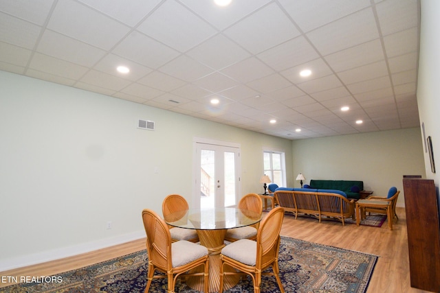 dining room with visible vents, wood finished floors, baseboards, french doors, and a paneled ceiling