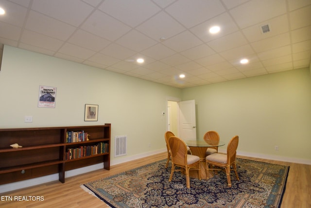 dining room featuring a drop ceiling, visible vents, baseboards, and wood finished floors