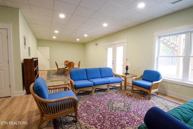 living room featuring wood finished floors, recessed lighting, french doors, a paneled ceiling, and baseboards