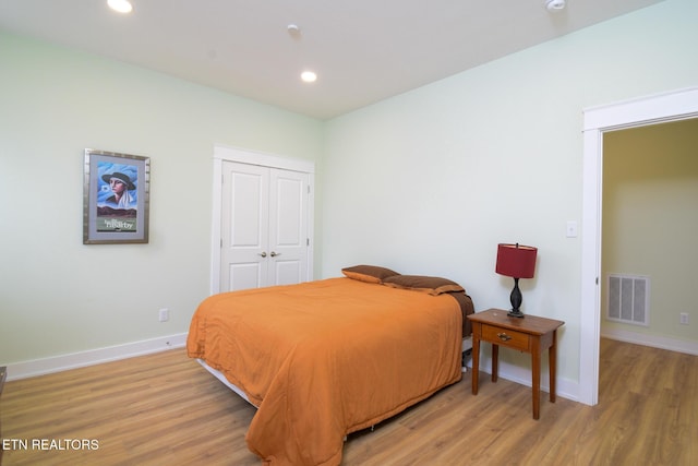 bedroom with light wood-style floors, visible vents, and baseboards