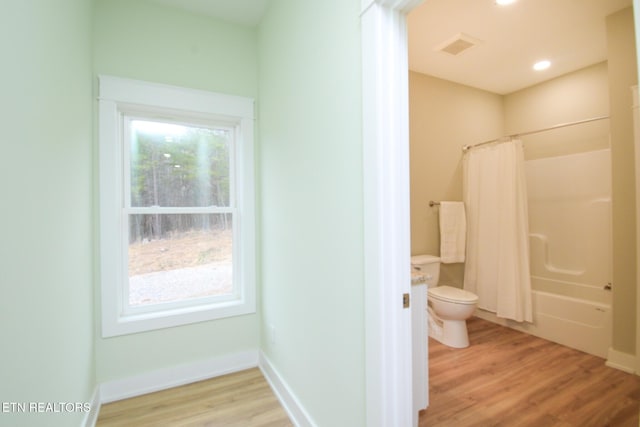 full bathroom with baseboards, toilet, a healthy amount of sunlight, and wood finished floors