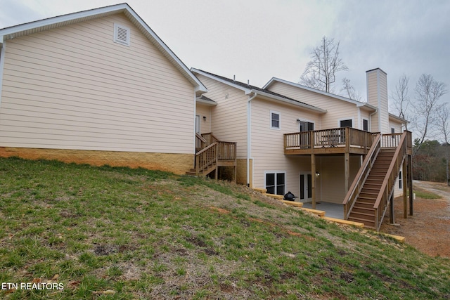 back of house featuring a yard, a chimney, a wooden deck, and stairs