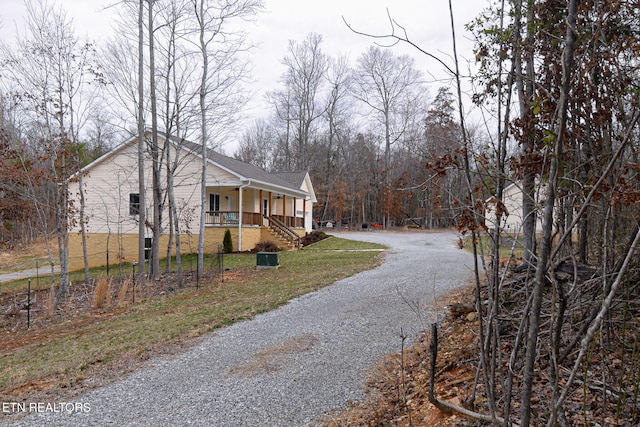 view of home's exterior featuring a lawn, a porch, and gravel driveway